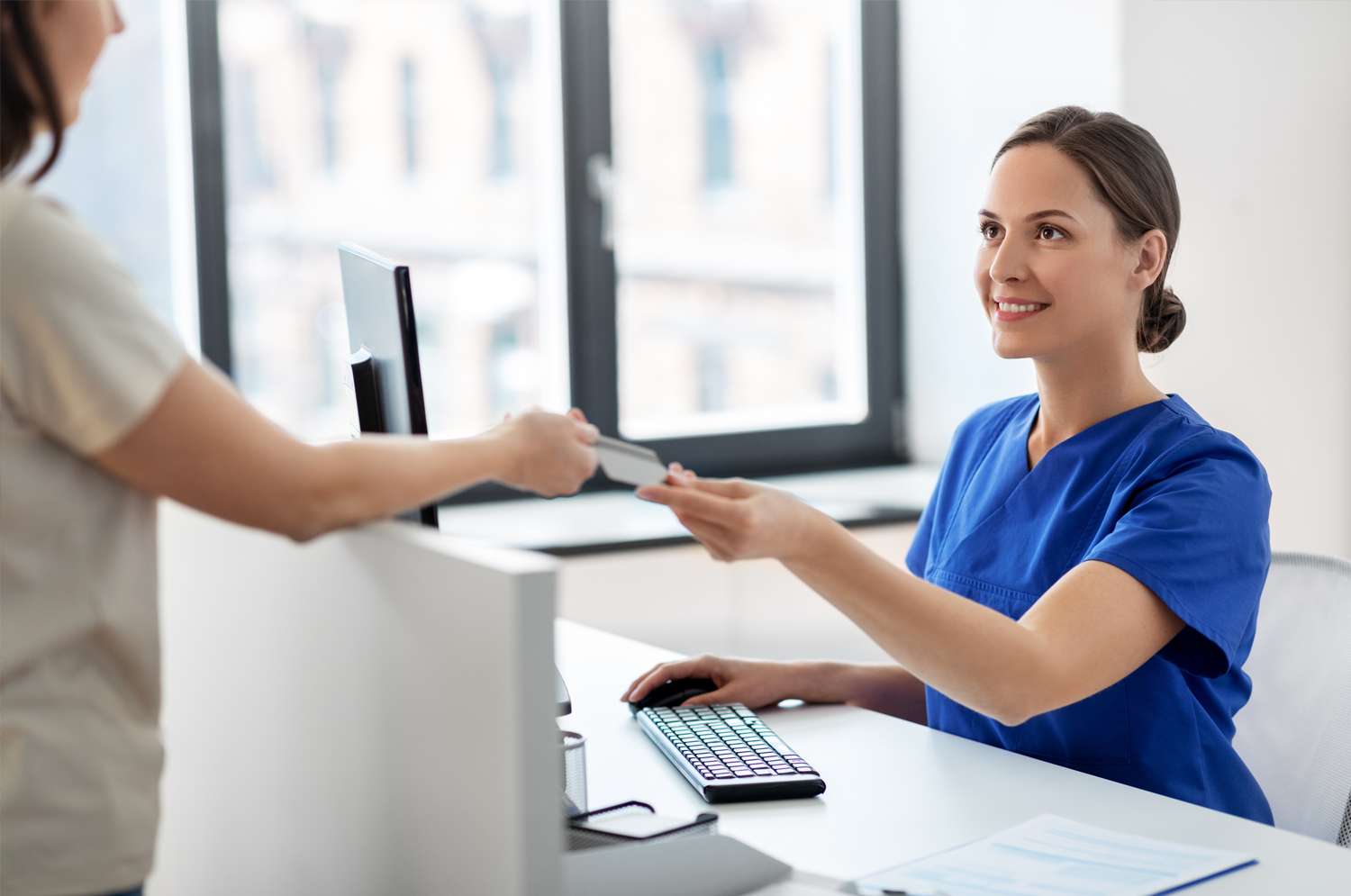 A patient and healthcare provider pass a credit card.